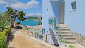 A coastal property with a clear view of the sea, a staircase leading to a balcony, and a parked car. - Esmerald Hotel (Ksamil)