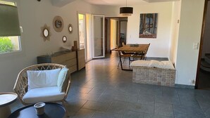 A spacious living area with a sofa, a dining table, and a bench. There is a sliding glass door leading to another room. - Superb villa in Puyvert Air conditioning, heated swimming pool, fully enclosed garden (Puyvert)