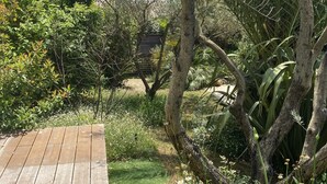 A wooden deck leading into a lush garden with various plants and trees. - Superb villa in Puyvert Air conditioning, heated swimming pool, fully enclosed garden (Puyvert)