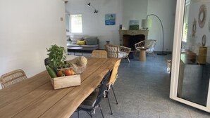 A dining area with a wooden table, wicker chairs, and a fruit basket. There is a fireplace with a mantel and wall art. - Superb villa in Puyvert Air conditioning, heated swimming pool, fully enclosed garden (Puyvert)