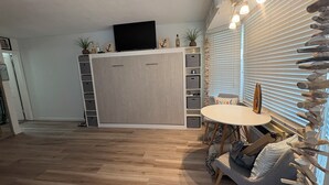 A modern living room with a large wooden cabinet, a flat-screen TV, and a dining area with a round table. - BEACH GETAWAY!! 🏖🏖🏖 (Wildwood Crest)