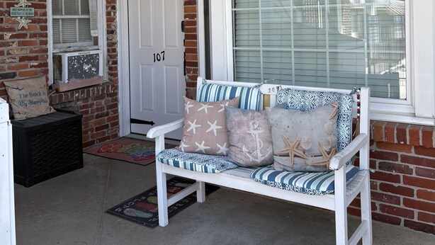 A porch with a white bench, a welcome sign, and a brick wall. - BEACH GETAWAY!! 🏖🏖🏖 (Wildwood Crest)
