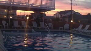 A pool area with lounge chairs and a building with a balcony overlooking the pool. - BEACH GETAWAY!! 🏖🏖🏖 (Wildwood Crest)