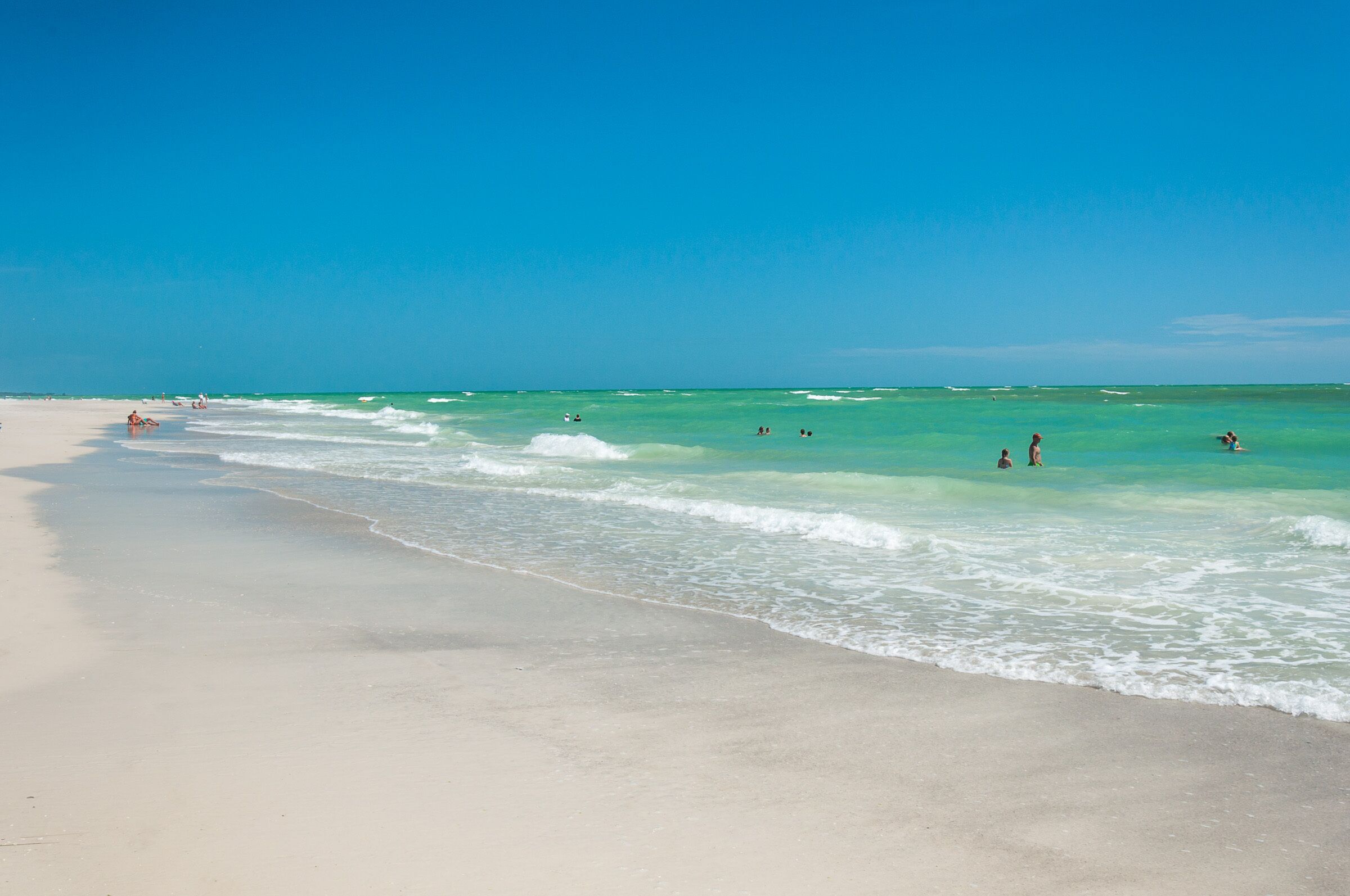 A beach with clear turquoise water and a sandy shore.