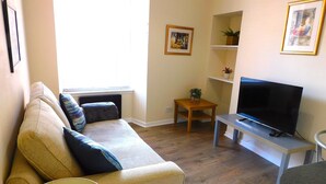A living room with a sofa, a television, a small table, and a window. - Fabulous location, One Bedroom West End Flat, just off Byres rd, close to SEC & Hydro (Glasgow)
