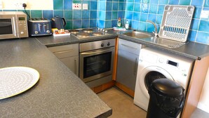 A compact kitchen with a microwave, toaster, stove, sink, and washing machine. - Fabulous location, One Bedroom West End Flat, just off Byres rd, close to SEC & Hydro (Glasgow)