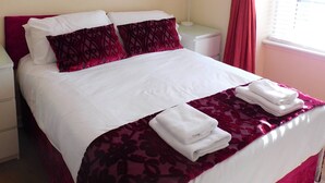 A neatly made bed with white and maroon bedding, a framed picture on the wall, and a window with red curtains. - Fabulous location, One Bedroom West End Flat, just off Byres rd, close to SEC & Hydro (Glasgow)