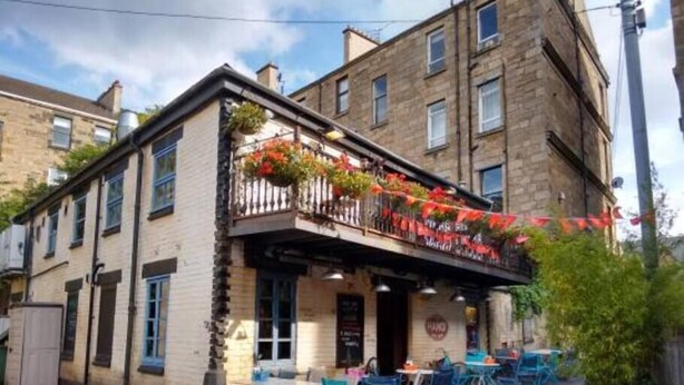 A building with a balcony adorned with flowers, outdoor seating, and a sign indicating a restaurant. - Fabulous location, One Bedroom West End Flat, just off Byres rd, close to SEC & Hydro (Glasgow)