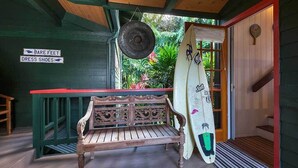 Un banco de madera, una tabla de surf y un cartel que dice 'Bare Feet Dress Shoes' en un porche.