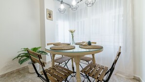 A round dining table with woven placemats, wooden chairs, and a vase with flowers. - MalagaSuite Cathedral Center (Málaga)