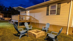 A house with a deck, outdoor seating, and a fire pit. - Cottage 304, 2 Bed w/ Fire Pit, near trails! (West Logan)