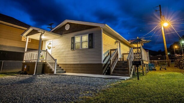 A two-story house with a covered porch and a staircase leading to the upper floor. - Cottage 304, 2 Bed w/ Fire Pit, near trails! (West Logan)