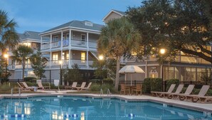 A pool area with lounge chairs and umbrellas, surrounded by buildings with balconies and a pool. - Edisto 1BR w/Beach Access & Resort Amenities (Edisto Island)