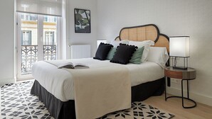 A neatly arranged bedroom with a bed, bedside table, and a view of the outside balcony. - Erregetxe by FeelFree Rentals (San Sebastián)