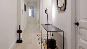 A hallway with a light wooden floor, a black metal console table with a basket, a mirror, and a framed picture on the wall. - Erregetxe by FeelFree Rentals (San Sebastián)