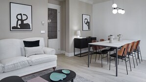 A modern living room with a white sofa, a dining table with chairs, and artwork on the walls. - Erregetxe by FeelFree Rentals (San Sebastián)