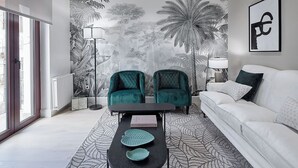 A modern living room with a large window, two teal armchairs, a white sofa, a black coffee table, and a patterned rug. - Erregetxe by FeelFree Rentals (San Sebastián)