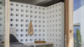 A modern bedroom with a bed, a hanging light, a wall with square cutouts, and a small table. - Exclusive & stylish villa. Concierge service included (Roses)