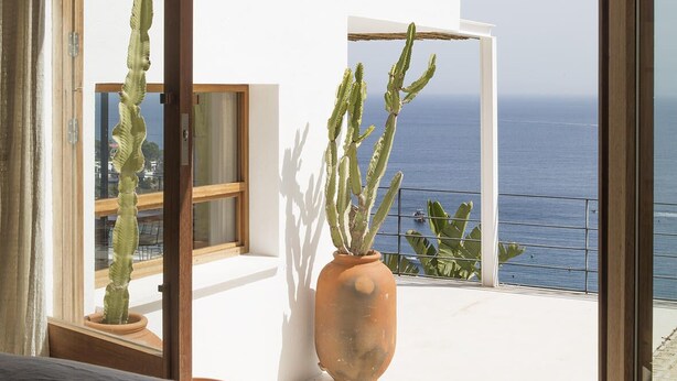 A bedroom with a large bed, a view of the sea through a balcony, and a cactus plant. - Exclusive & stylish villa. Concierge service included (Roses)