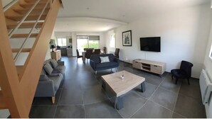 A spacious living area with a staircase, a sofa, a coffee table, and a TV.