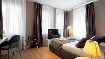 Una habitación de hotel moderna con una cama, un escritorio, una silla, un televisor y una lámpara.