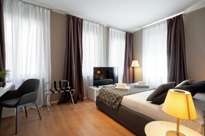 Ein modernes Hotelzimmer mit Bett, Schreibtisch, Stuhl, Fernseher und Lampe.