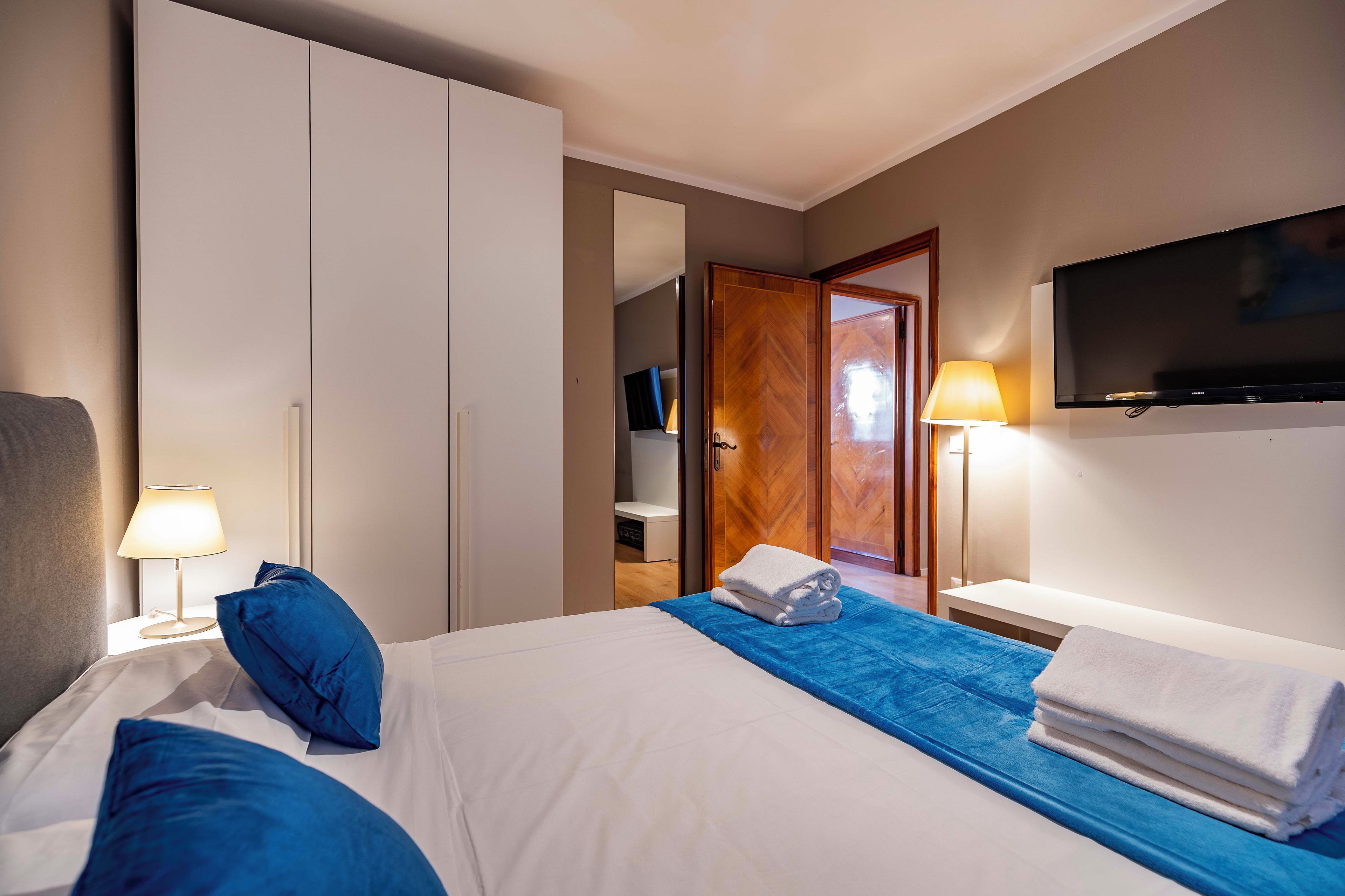 Een hotelkamer met een bed, een televisie, een kast en een spiegel.