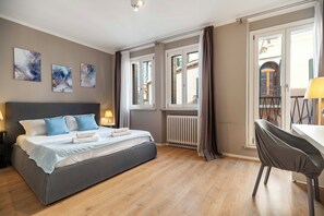Ett hotellrum med en säng, sängbord, konstverk, ett element och utsikt över omgivningen.