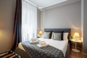 A hotel room with a large bed, two bedside tables with lamps, a chair, and a window with curtains. - San Marco Boutique by Wonderful Italy (Venice)