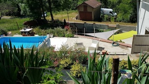 Un patio trasero residencial con piscina, un cobertizo pequeño y un vehículo estacionado.