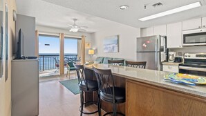 Cocina moderna con barra, refrigerador, microondas, horno y una mesa de comedor con sillas.