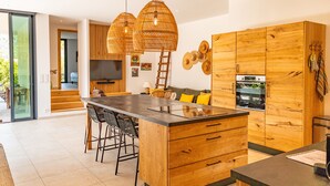 Une cuisine moderne dotée d’un îlot central, de meubles en bois et d’un coin repas avec des tabourets de bar.