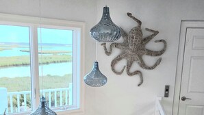 A room with a view of a water body, a white railing, and decorative wall art including an anchor and an octopus. - Sunrise-Sunset Views From Waterfront Home w/ Elevator (just renovated) (Bethany Beach)