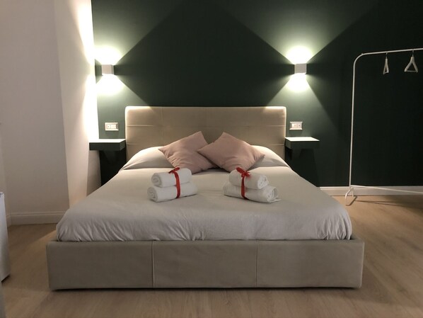 Relax in a spacious room with a large bed, featuring a neutral-toned headboard and light-colored mattress.