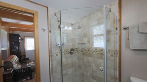 Douche met glazen deuren, een badkuip en toilet.