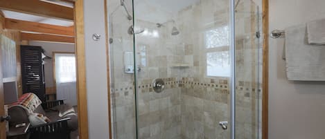 Ducha con puertas de vidrio, cabezal de ducha visible y pared con azulejos.
