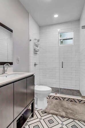 Un baño moderno con lavamanos blanco, inodoro y zona de ducha.