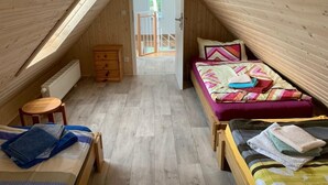 A small, cozy attic bedroom with a sloped ceiling, a wooden dresser, a bed with colorful bedding, and a small table. - Ferienwohnung im Igelbau (Baabe)