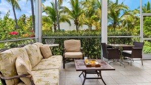 A balcony with a sofa, chairs, and a table with a tray of fruit.