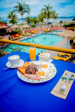 A breakfast table with a plate of food, a glass of orange juice, and a cup of coffee. - Hotel Yadran (Puntarenas)