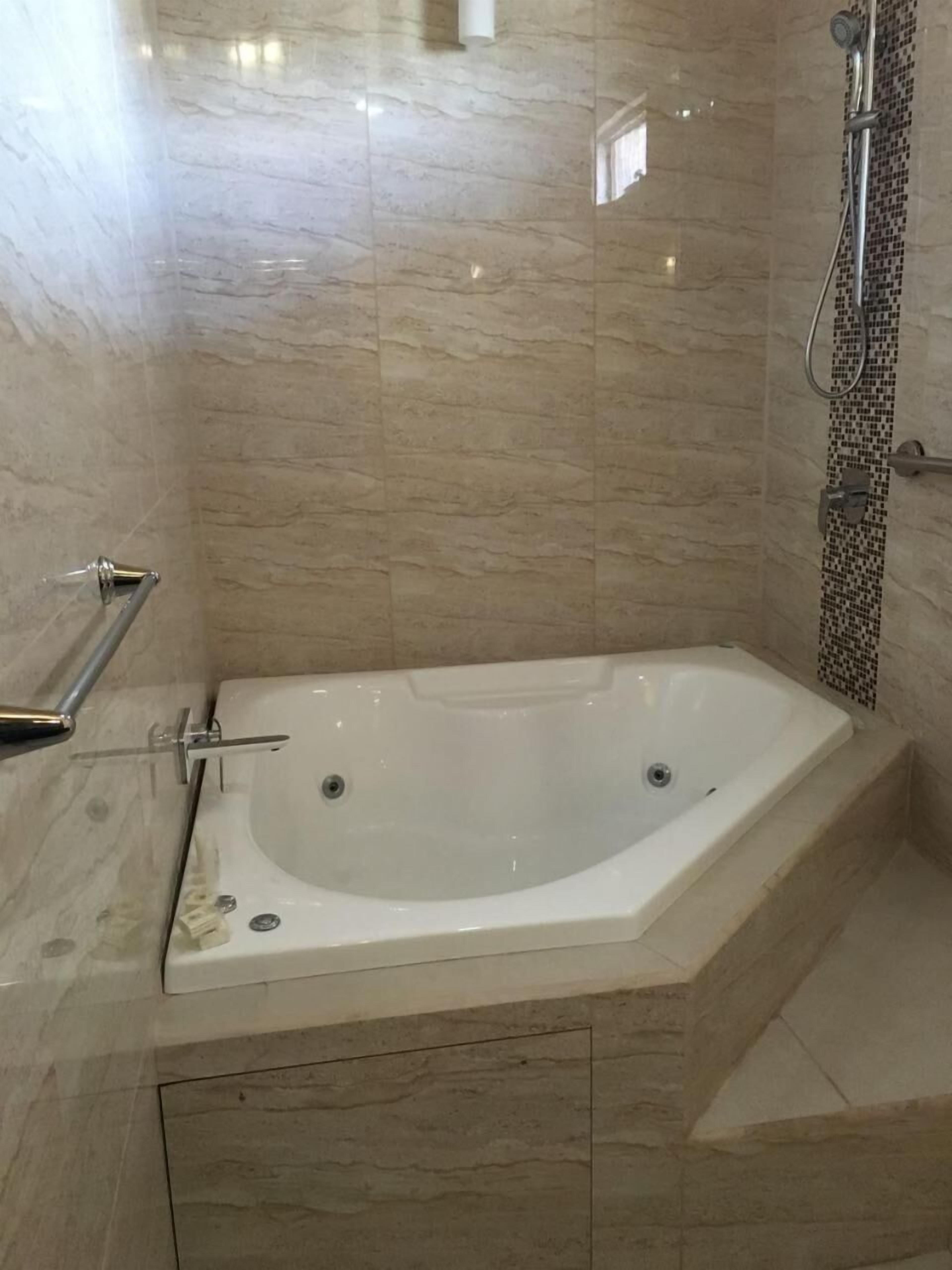 Een badkamer met een vrijstaand bad, een douchegedeelte en een betegelde vloer.