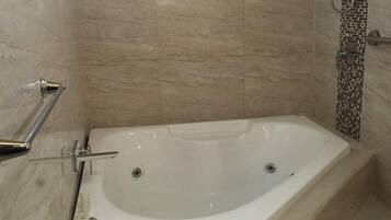 Een badkamer met een vrijstaand bad, een douchegedeelte en een betegelde vloer.