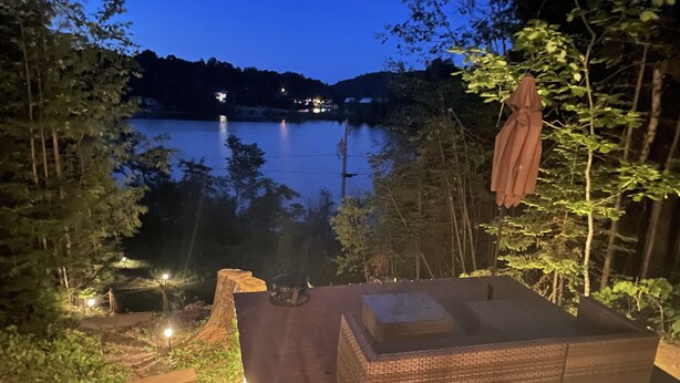A wooden deck with a built-in seating area overlooking a lake, surrounded by trees.
