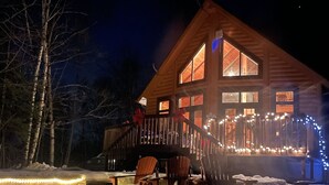 A wooden cabin with a deck, surrounded by snow.