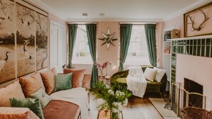 Un salon chaleureux avec un canapé, un fauteuil vert, une cheminée et une grande décoration en forme d’étoile accrochée au mur.