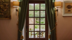 Une porte en bois ornée d’un motif à carreaux, flanquée de rideaux verts et de lampes fixées au mur.