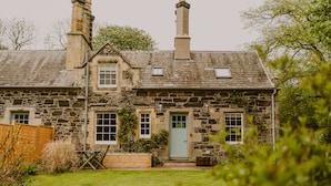 Une maison en pierre avec un toit en pente, une porte d’entrée et un petit porche.