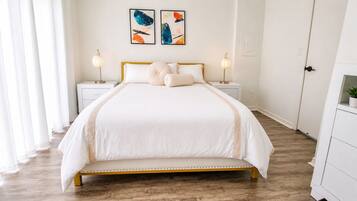 A neatly arranged bedroom with a bed, bedside tables, and a nightstand.