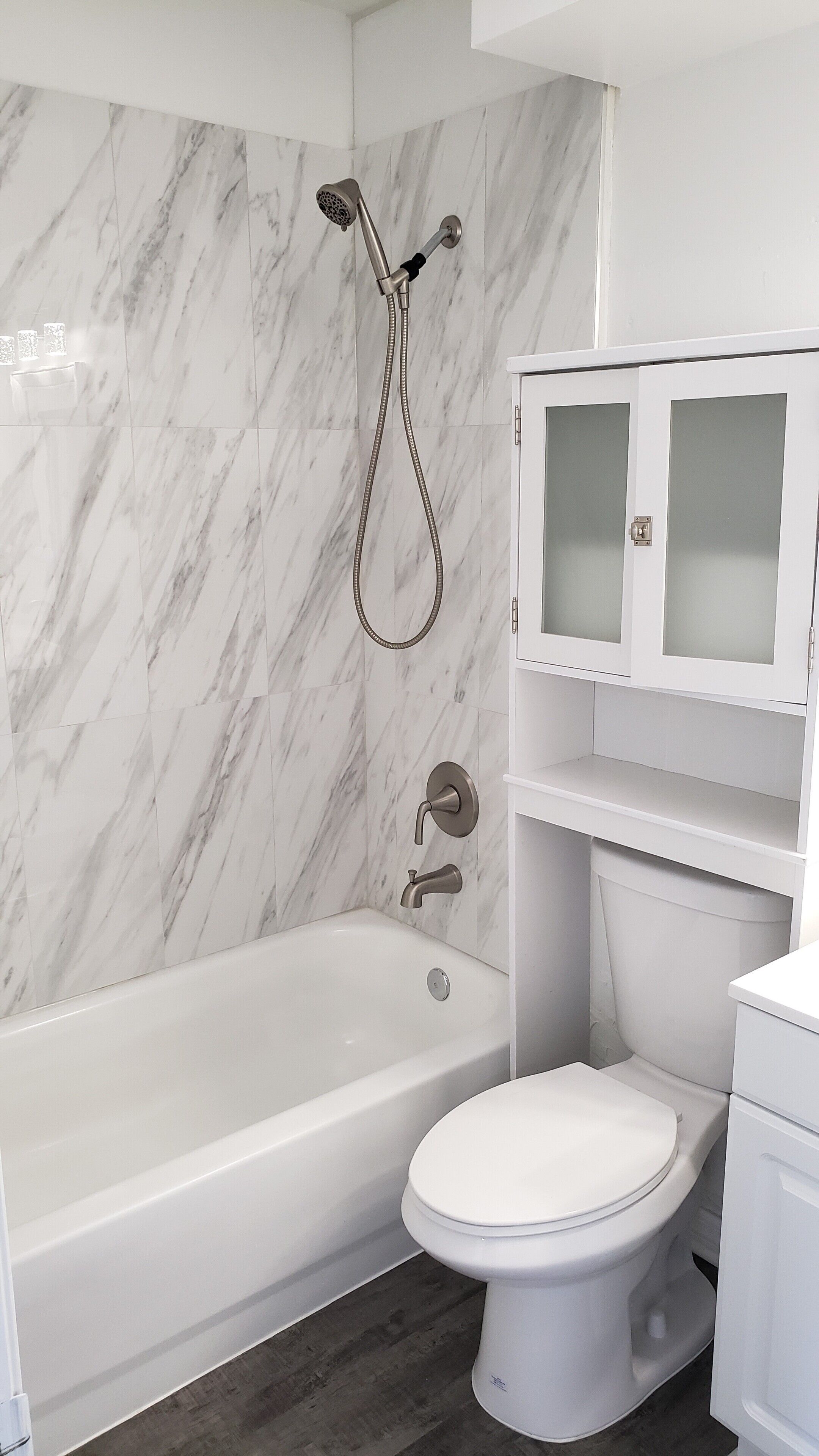 Une salle de bain avec une baignoire blanche, des toilettes et un meuble avec des portes en verre dépoli.