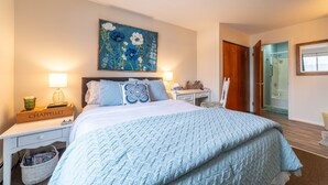 A bedroom with a large bed, a nightstand with a lamp, a dresser, and a painting on the wall. - Awesome in Walloon Village (Walloon Lake)